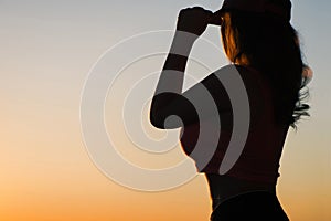 Young woman after jogging on the sunset backgrounds. Top view on the city