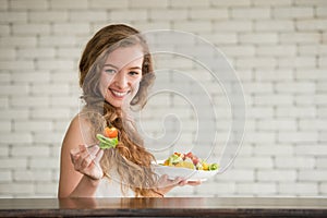 Young woman in joyful postures with salad bowl on the side