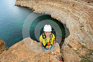 Young woman jump from the cliff with a rope. Ropejumping.