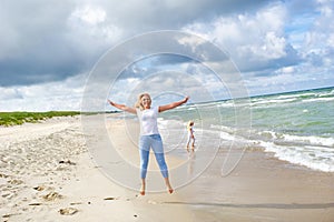 Young woman jumping on the beach of the Baltic Sea in Lithuania. Little girl stroll along the beach