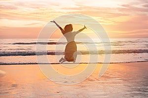 Young woman jumping on the beach at beautiful sunset, Summer vacation concept