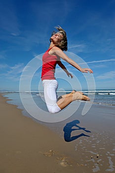 Young woman jumping on the beach in summer