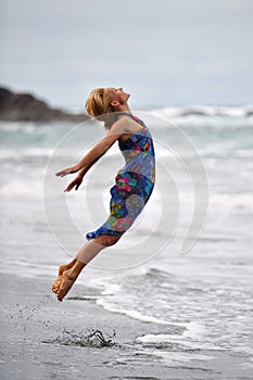 Young woman jumping on the beach in summer