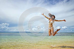 Young woman jumping at the beach on Taveuni Island, Fiji