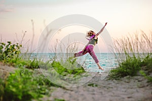 Young woman jumping on the beach towards the sea