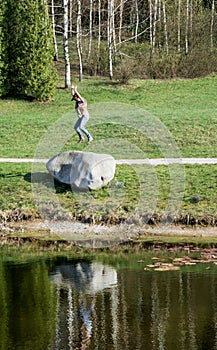 Young woman jumping on the big stone