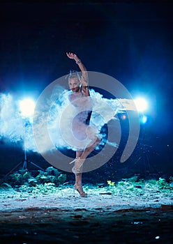 Young woman jumping in blue powder cloud