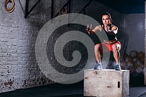 Woman jumping box. Fitness woman doing box jump workout at cross fit gym. photo