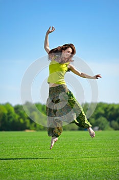 Young woman jumping on a green meadow