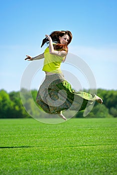 Young woman jumping on a green meadow