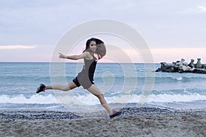 Young woman jumping happy at the beach, working out photo