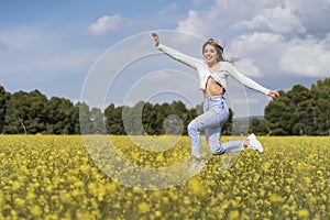 young woman jumping happy in a field of yellow flowers