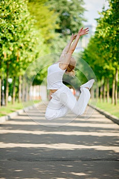 Young woman jumping high in city park