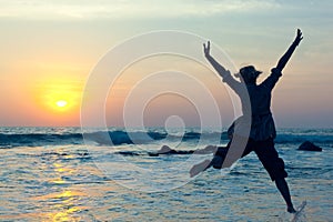 Young woman jumping with joy over the water