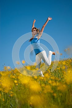 Young woman is jumping in a meadow