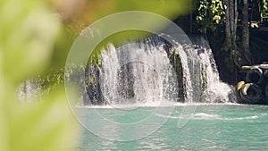 Young woman jumping in mountain lake from rope and splashing waterfall on background. Slow motion. Happy woman jumping