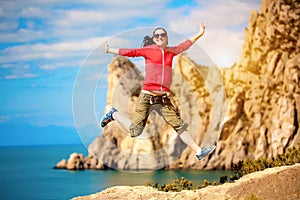 Young woman is jumping over mountain peak