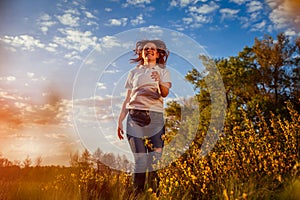 Young woman jumping, running and having fun in spring field at sunset. Happy and free girl relaxes and enjoys nature