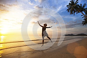 Young woman jumping on the sea coast during the amazing sunset.