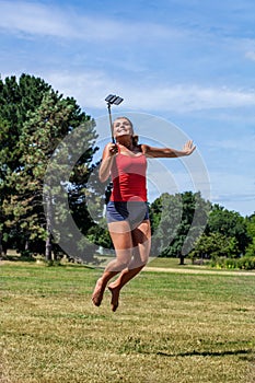 Young woman jumping and smiling with cell phone outdoors