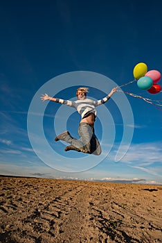 Young woman jumping with toy balloons