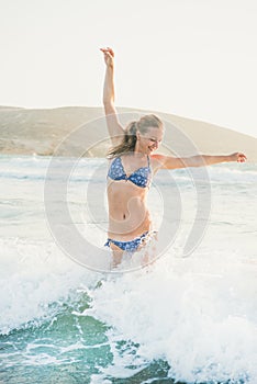 Young woman jumping in wavy waters of Mediterranean sea, Rhodes