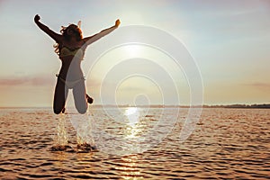 Young Woman Jumps on Beach at sunset