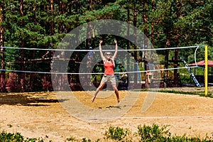 A young woman jumps on the volleyball field at the beach