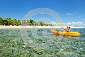 Young woman kayaking near South Sea Island, Mamanuca islands group, Fiji