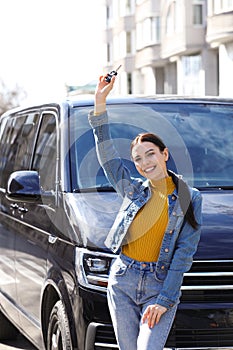 Young woman with key near car on street. Buying new auto