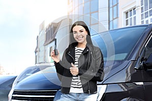 Young woman with key near car on street. Buying new auto