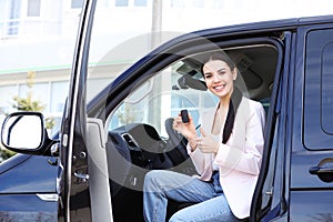 Young woman with key sitting in car. Buying new auto