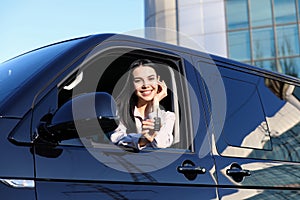 Young woman with key sitting in car. Buying new auto