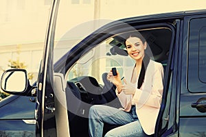 Young woman with key sitting in car. Buying new auto