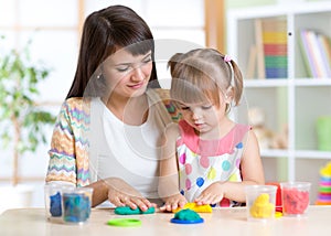 Young woman and kid playing with colorful clay