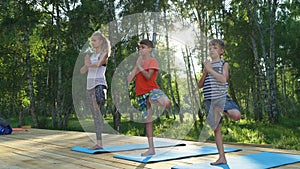 Young woman and kids performing yoga