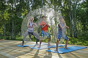 Young woman and kids performing yoga