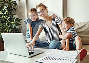 Young woman with kids working with laptop at home