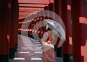 Young woman in a kimono holding an umbrella walks down the aisle