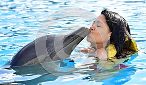 Young woman kissing dolphin in pool