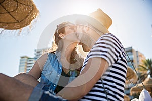 Young woman kissing her boyfriend on forehead in sunlight