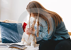 Young woman kissing her corgi puppy on bed at home