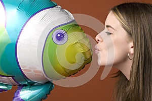 Young woman kissing an inflatable fish toy