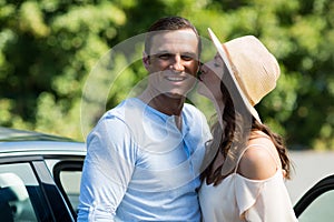 Young woman kissing man by car