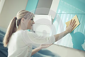 Young woman in the Kitchen doing Housework cleaning cupboards