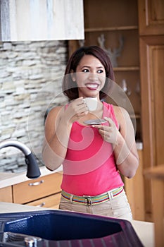 Young woman in kitchen drinking coffee