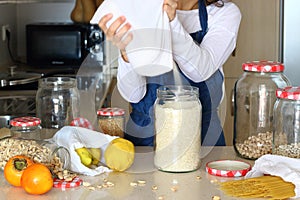 Young woman in kitchen with grocery shopping in bulk.