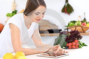 Young woman at the kitchen making online shopping by tablet computer and credit card