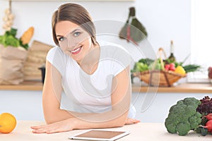 Young woman at the kitchen making online shopping by tablet computer and credit card