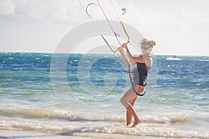 Young woman kite surfer getting ready for kiting on sand tropica